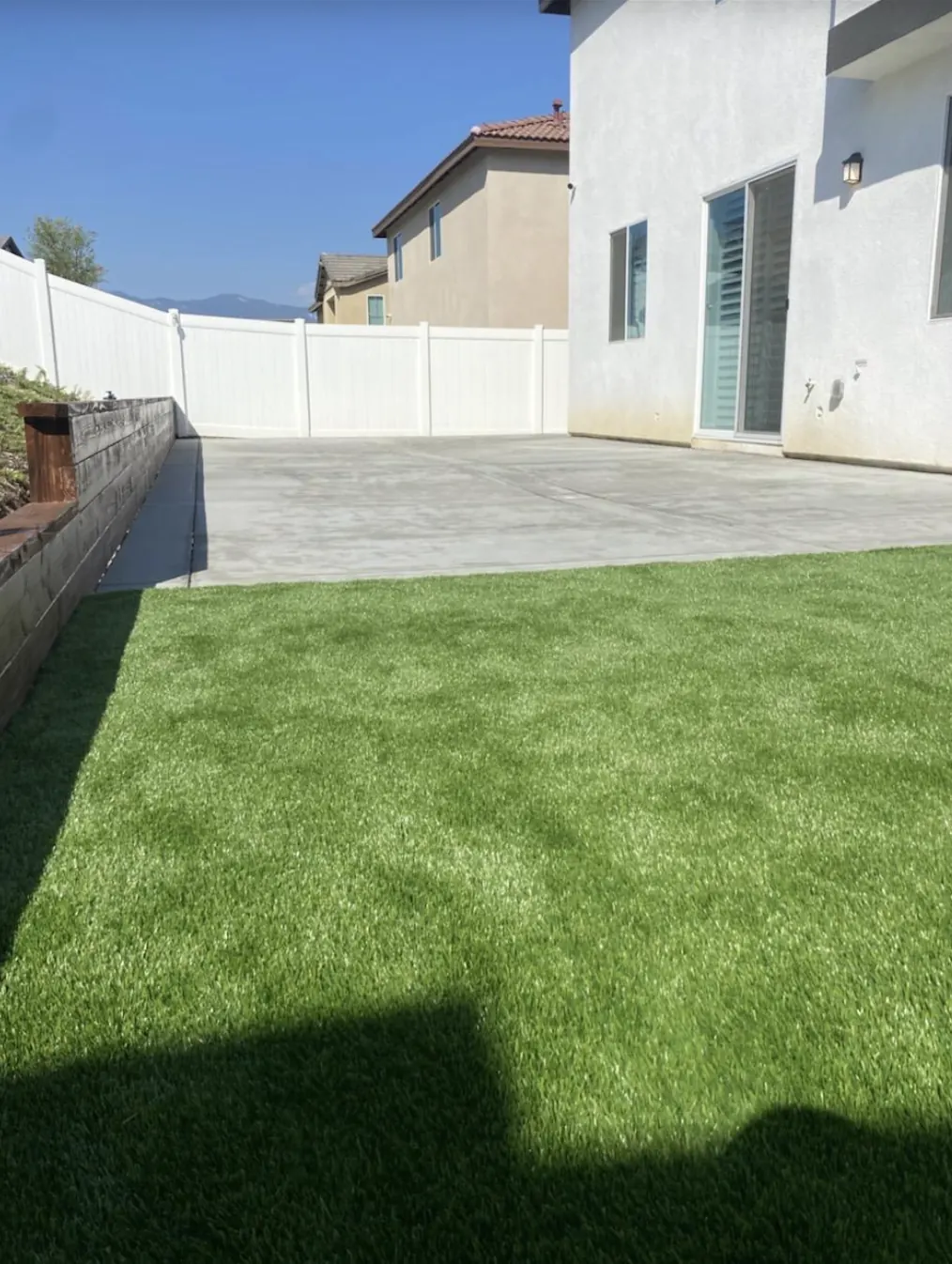 Finished back yard with artificial grass and a concrete patio