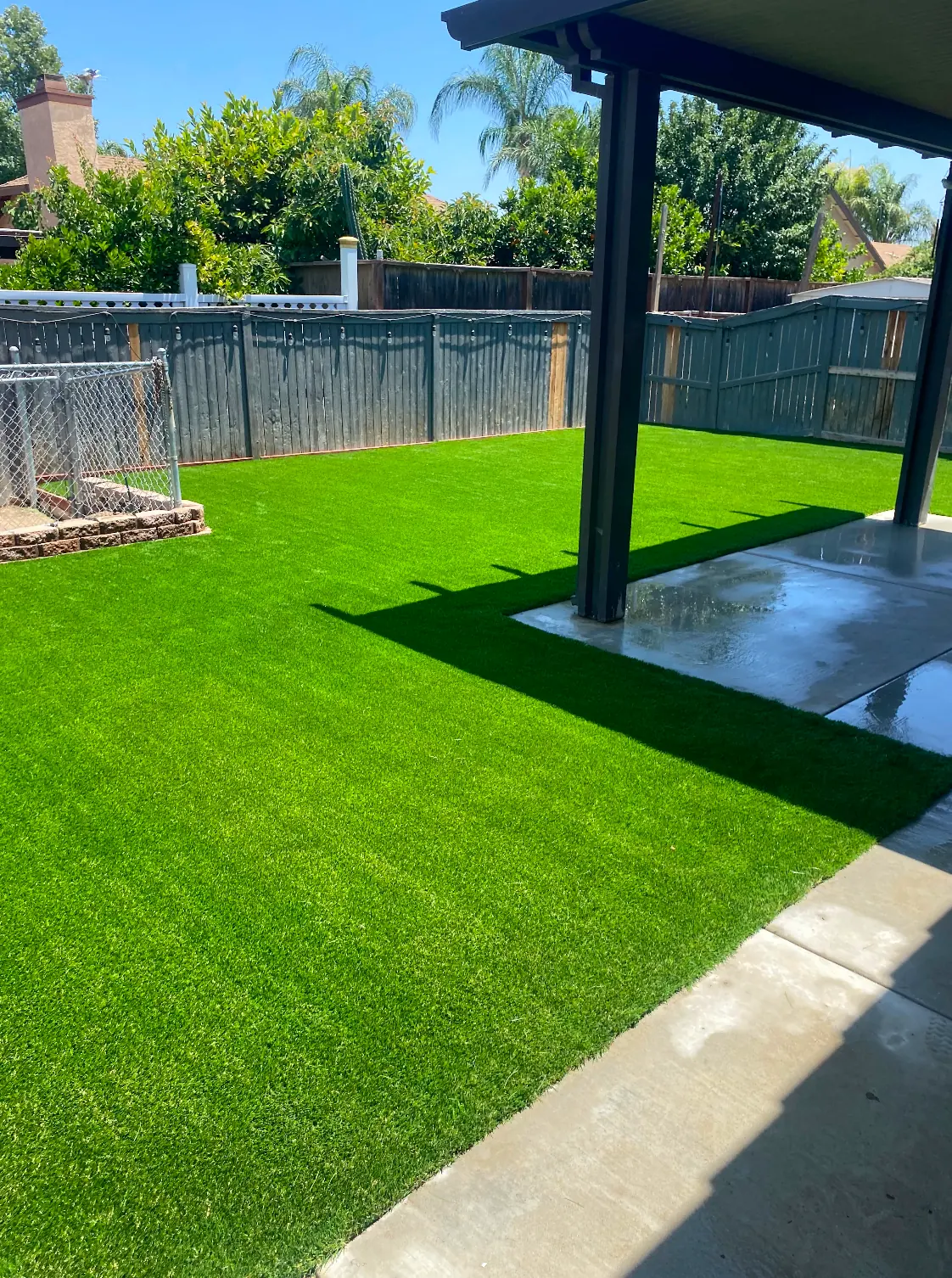 Freshly poured concrete beside artificial grass in a Perris, CA back yard