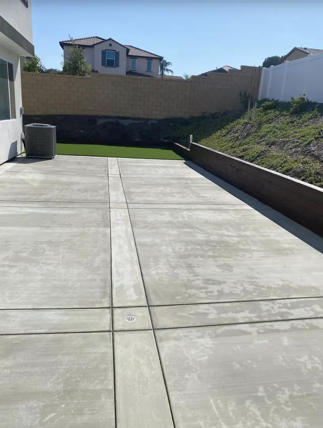 New patio slab beside a retaining wall and artificial grass