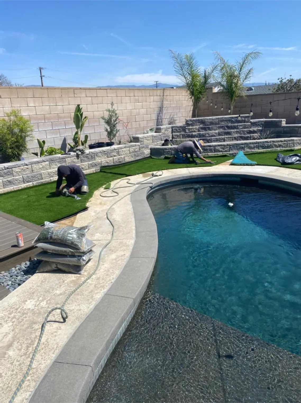 Pool deck with a stone planter wall and artificial grass going in
