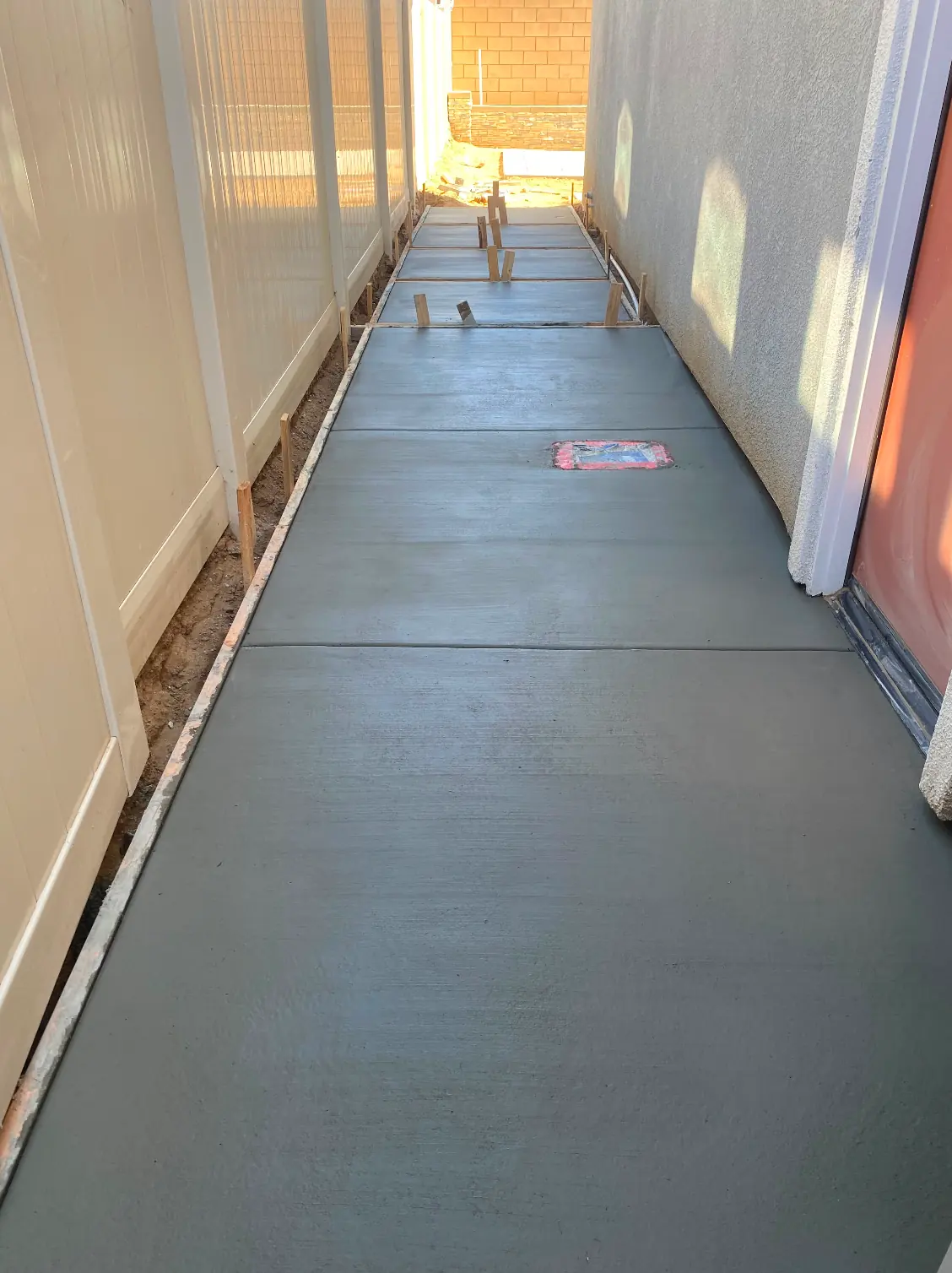 Freshly poured concrete walkway in a narrow side yard in Perris, CA